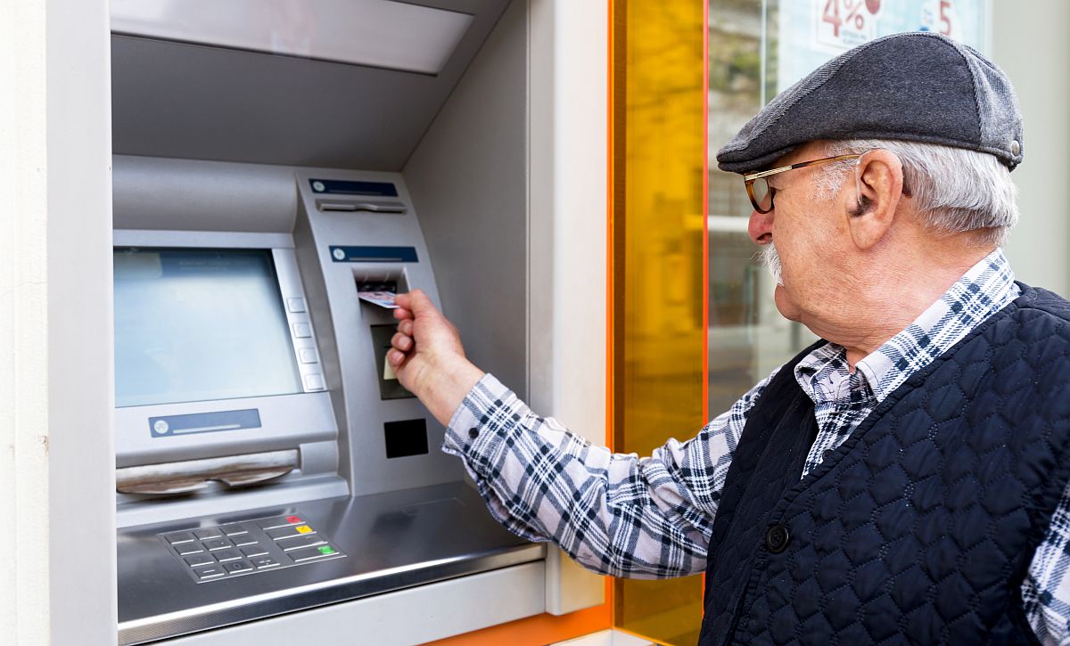 Nyugdíjas egy bankautomatába helyezi a bankkártyáját.