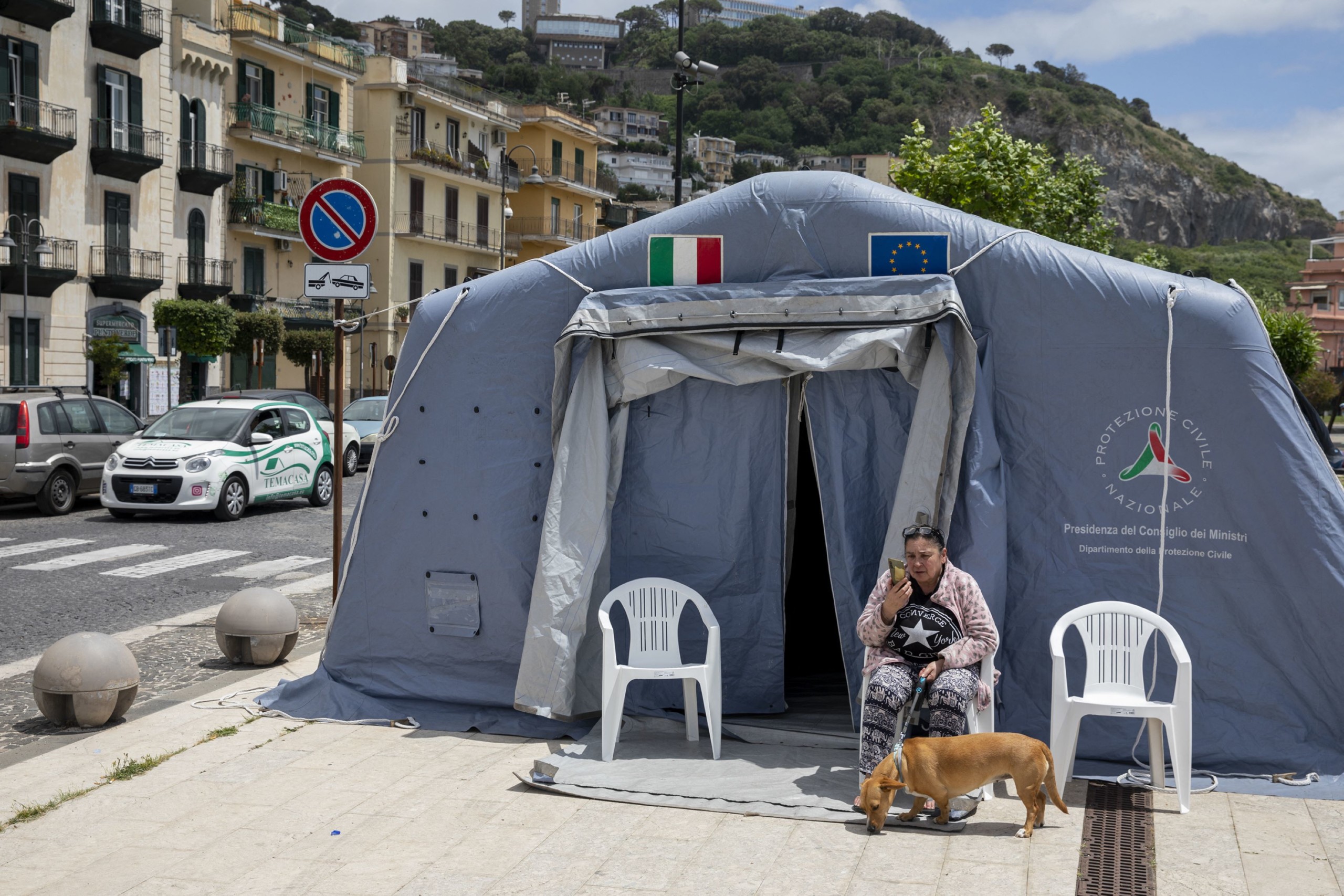 Egy nő és a kutyája a földrengés után felállított sátortáborban Nápolyban május 21-én.