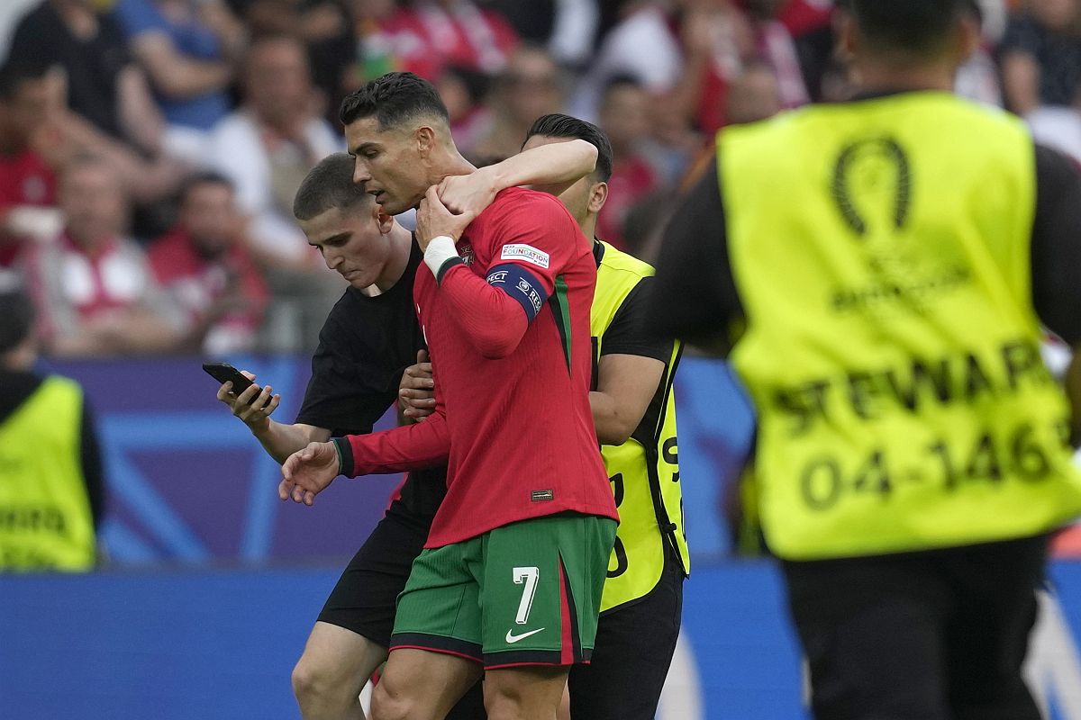 A portugál Cristiano Ronaldóval (b2) próbál közös képet készíteni egy pályára beszaladt férfi a 2024-es németországi labdarúgó Európa-bajnokság F csoportja második fordulójának Törökország-Portugália mérkőzésén a dortmundi Westfalen Stadionban 2024. június 22-én.