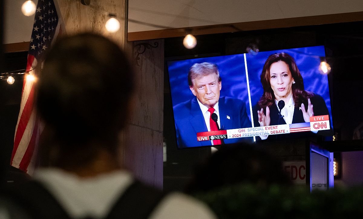 Egy járókelő nézi egy tévé képernyőjén Donald Trump és Kamala Harris televíziós vitáját.