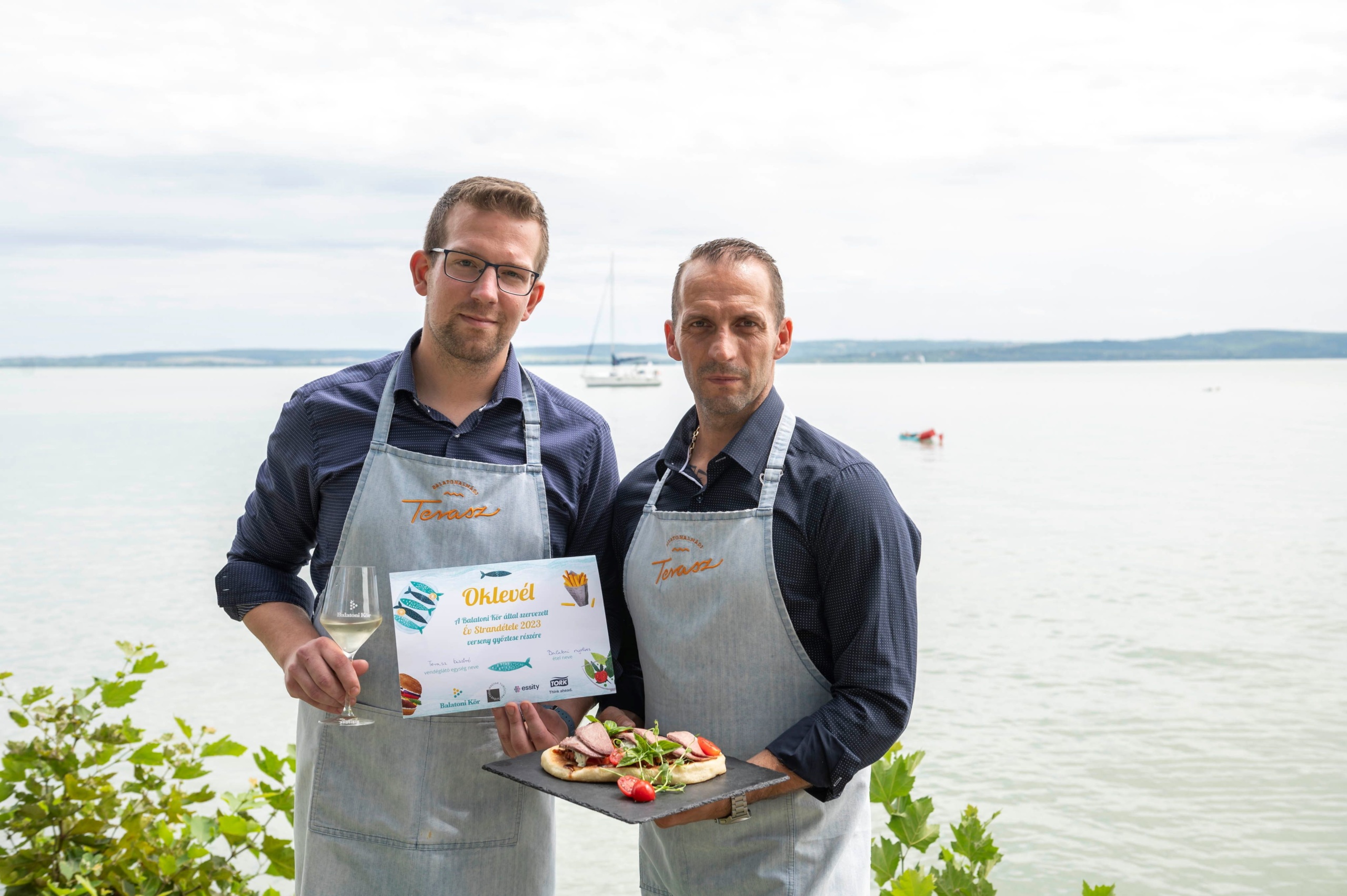 Bánfi Bence, a balatonalmádi Terasz Bisztró séfje (b) és Nagy Gábor, a bisztró tulajdonosa az Év Strandétele győztes ételével, a Balatoni nyelvessel a verseny díjátadóján, Balatonudvari fövenyesi strandján 2023. augusztus 3-án.