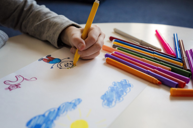 Kisgyermek rajzol színes ceruzákkal.