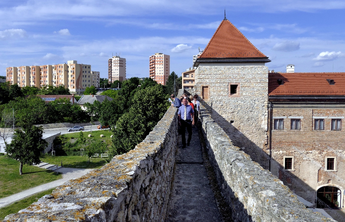 Turisták sétálnak körbe nézelődve a Thury-vár helyreállított gyilokjáróján, elhaladva az ugyancsak visszaépített negyedik vártorony mellett.