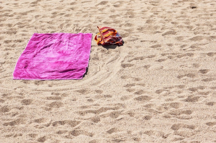 Rózsaszín törölköző és szandál a homokos parton Magyarországon
