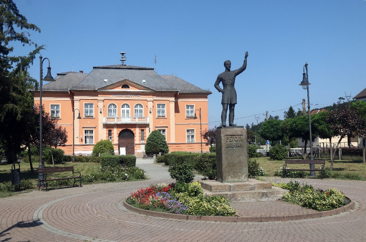 Petőfi Sándor szobra a Petőfi Sándor téren, háttérben az Ózdi Városi Könyvtár Ózdon 2023. augusztus 21-én.