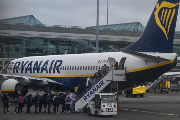 Turisták állnak sorban a Ryanair repülőgépe mellett.