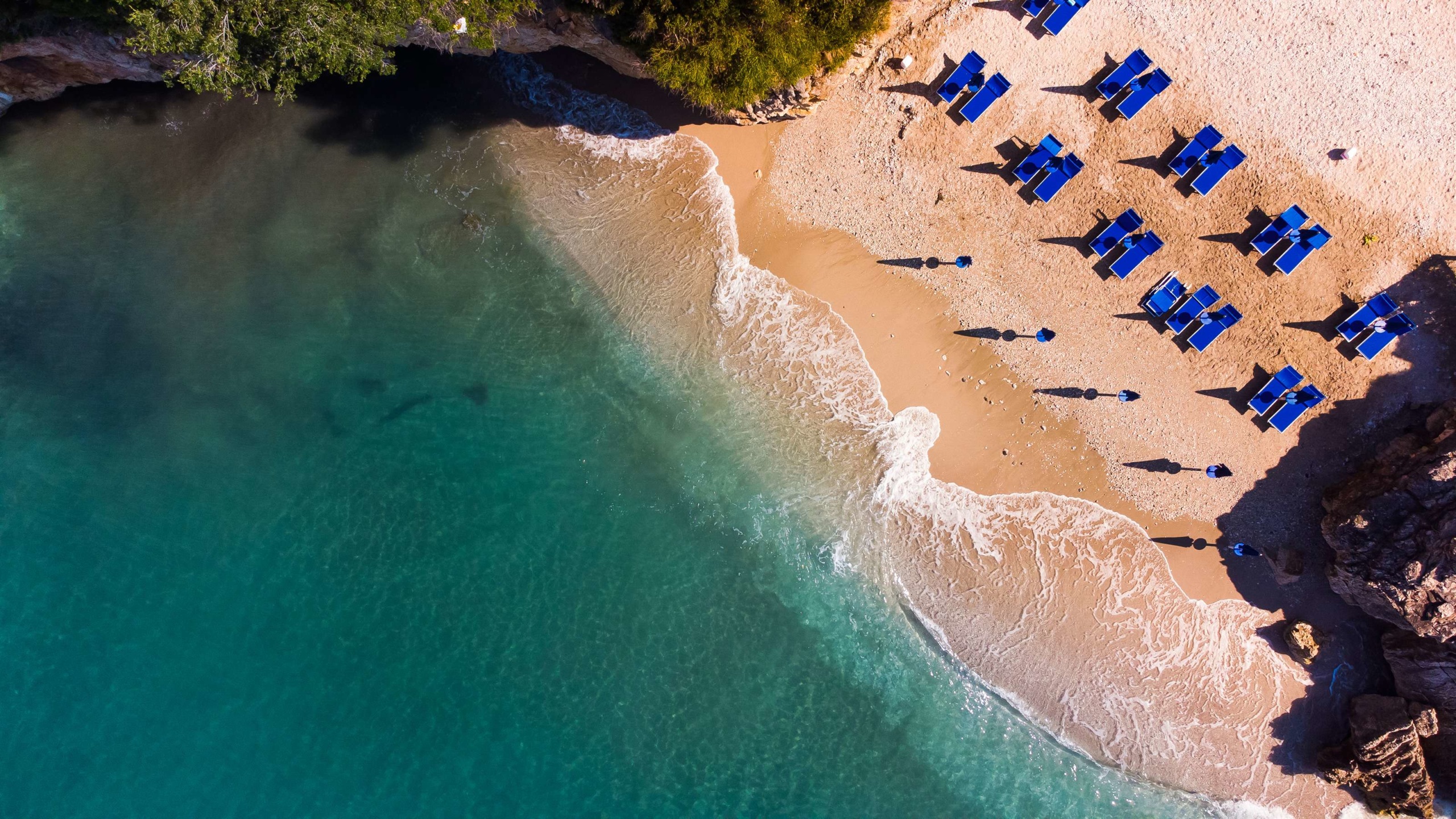 A Gjipe strandon felülnézetből láthatóak a kék napernyők