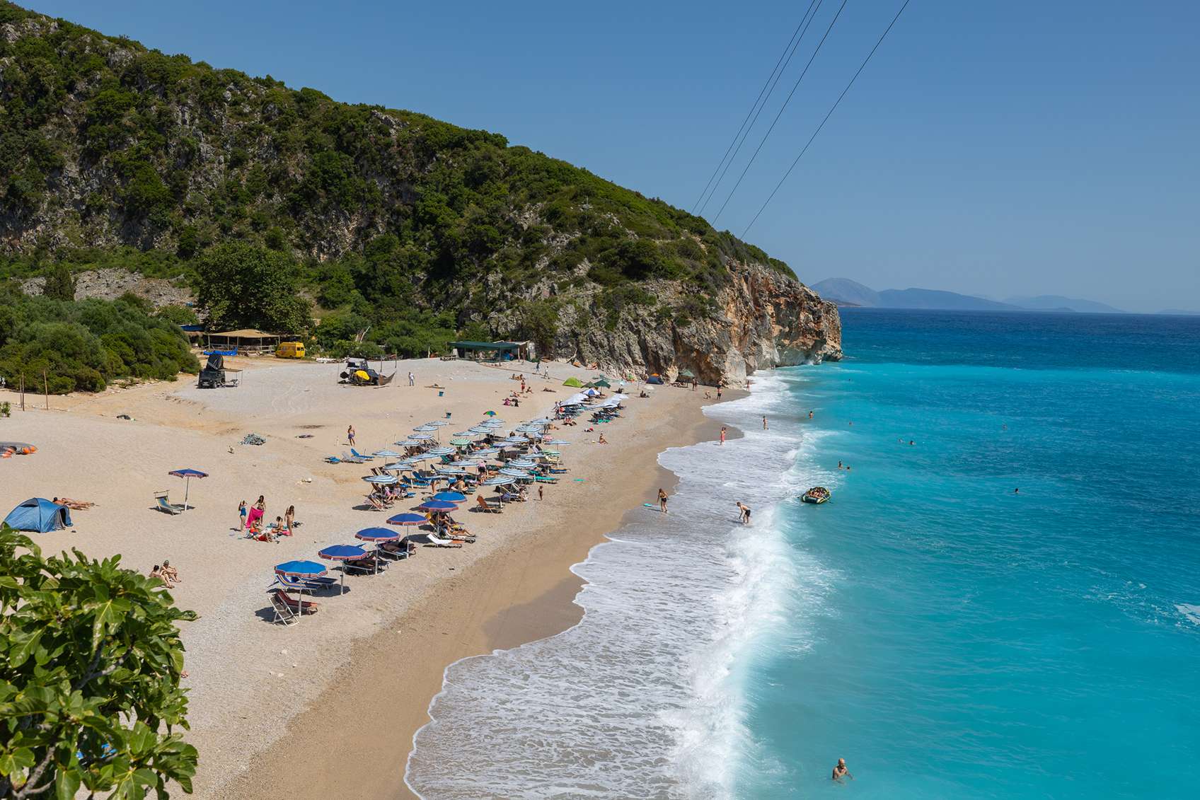 Gyönyörű strand Albániában nyugágyak fürdőzők és napernyők is láthatóak