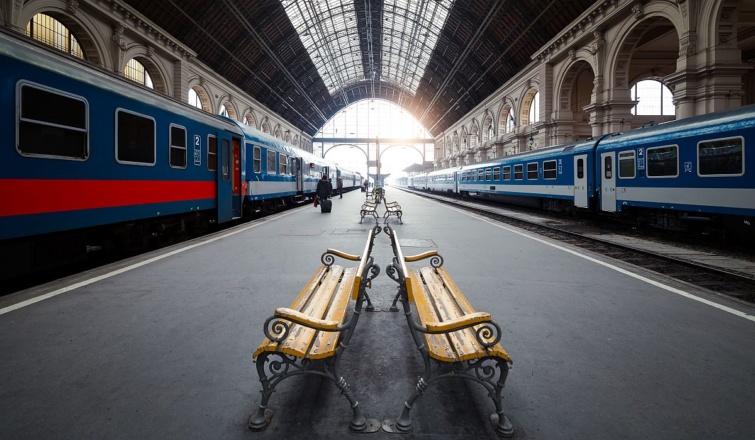 Vonatszerelvények és padok a peronon a budapesti Keleti pályaudvaron.