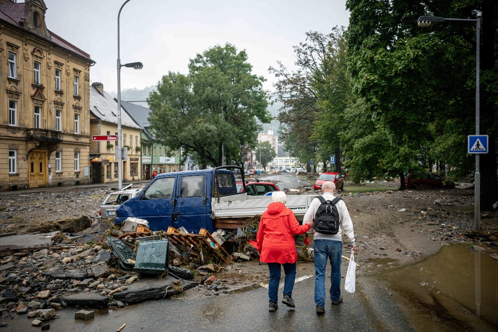 Emberek sétálnak a rongálódott utcán