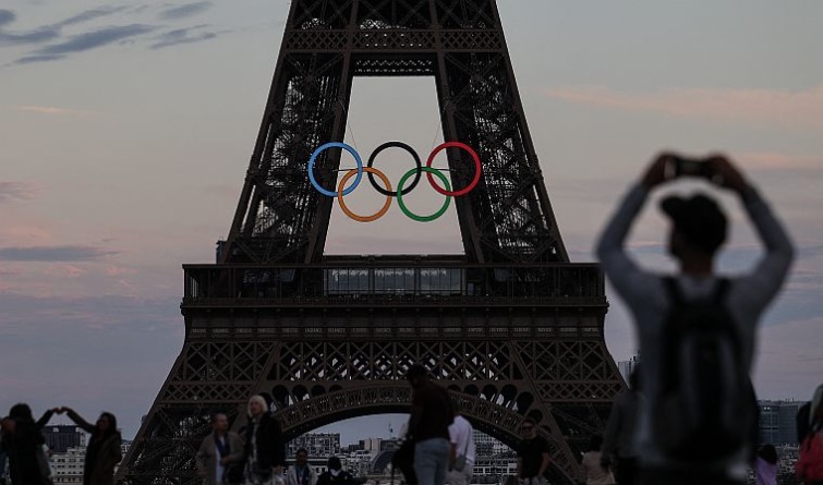 Az olimpiai ötkarikás Eiffel-tornyot fotózza egy férfi.