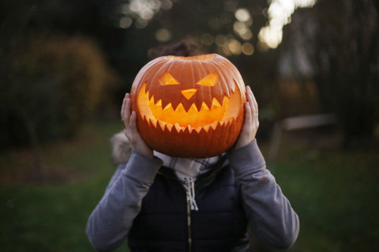 Halloween töklámpást tart fejétkitakarva egy kisgyerek