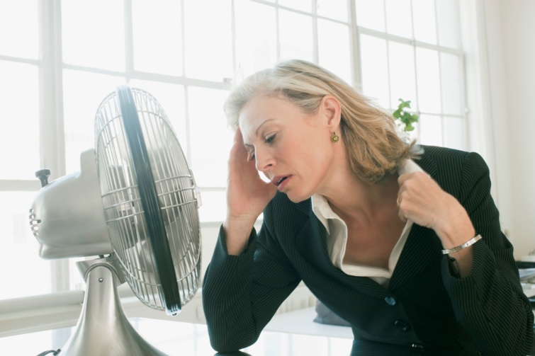 Ventilátor előtt ülő nő a hőségben.