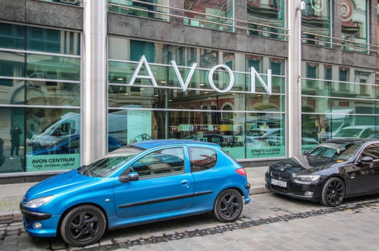 Avon kirakat előtt kék autó parkol