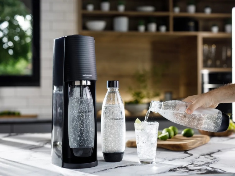 soda stream gép és palack éppen egy pohárba töltenek belőle